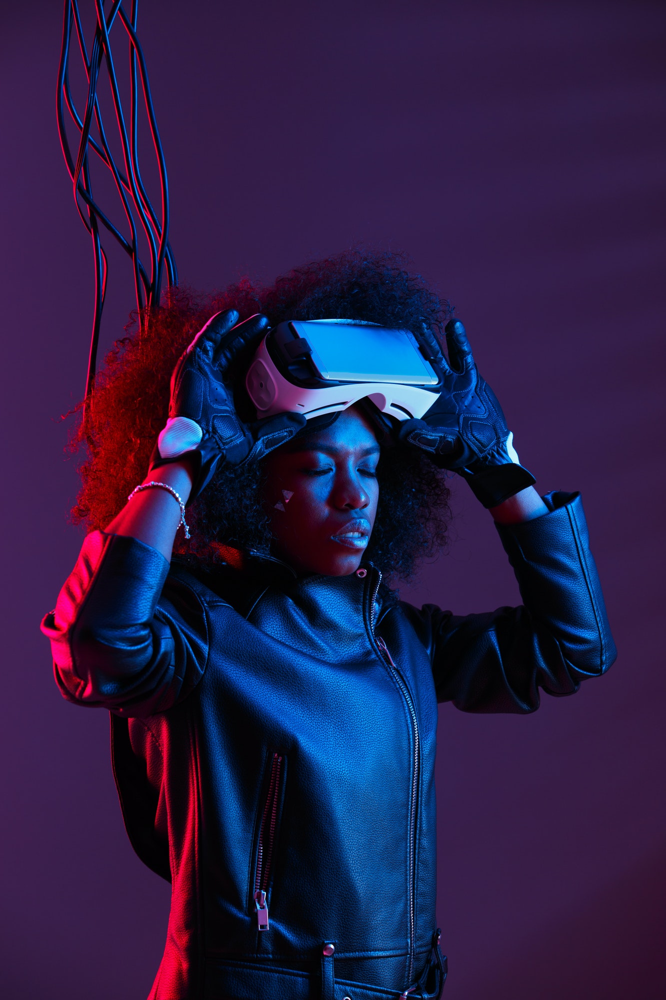 curly dark haired girl dressed in a black leather jacket and gloves is wearing the virtual reality Golden